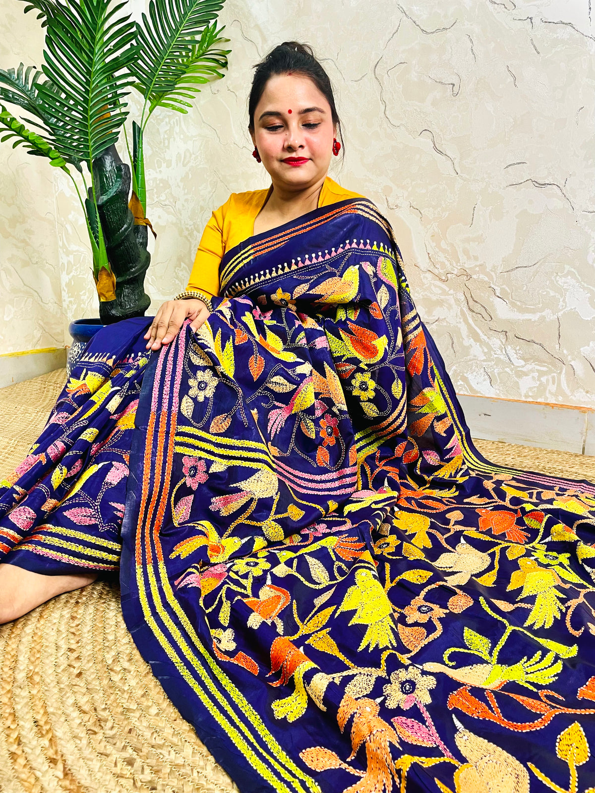 Woman seated in royal blue corner-to-corner Kantha silk saree, side pallu view