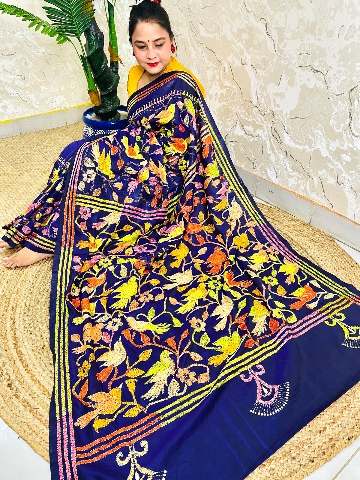 Woman seated in royal blue corner-to-corner Kantha silk saree, side pallu view