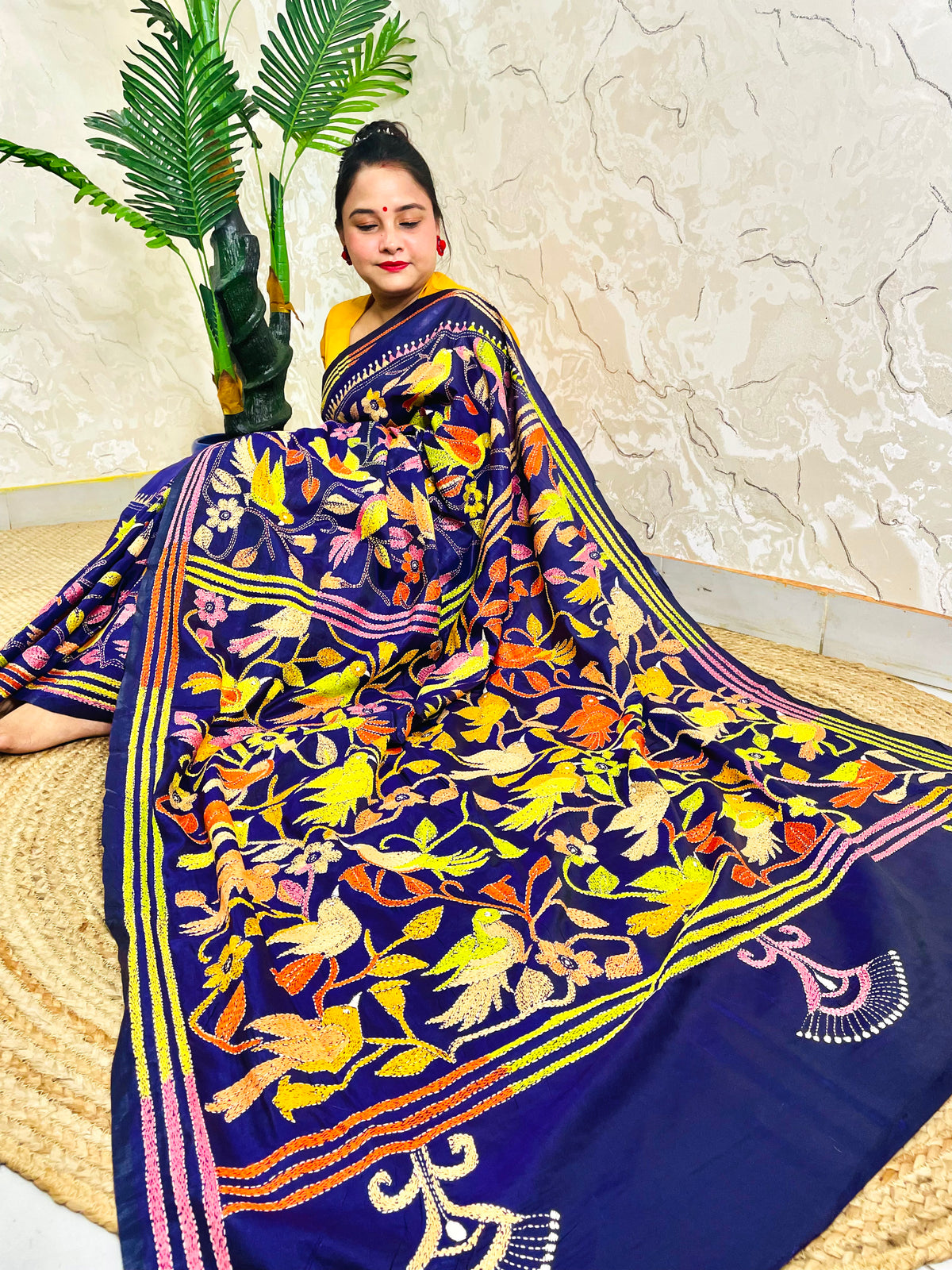 Woman seated in royal blue corner-to-corner Kantha silk saree, side pallu view
