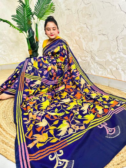 Woman seated in royal blue corner-to-corner Kantha silk saree, side pallu view