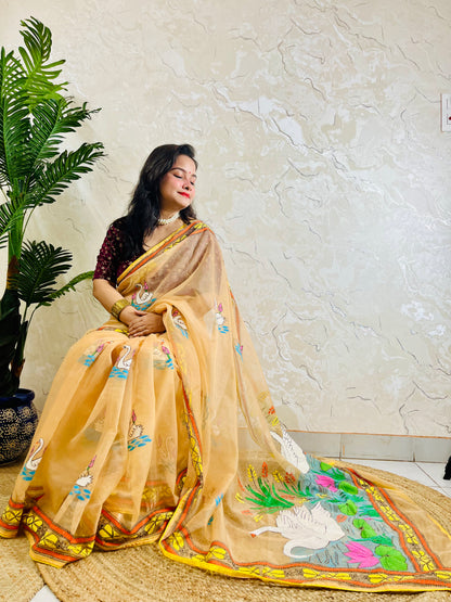 Woman seated in beige-gold Kantha stitch organza saree with swan and lotus embroidery, pallu draped forward