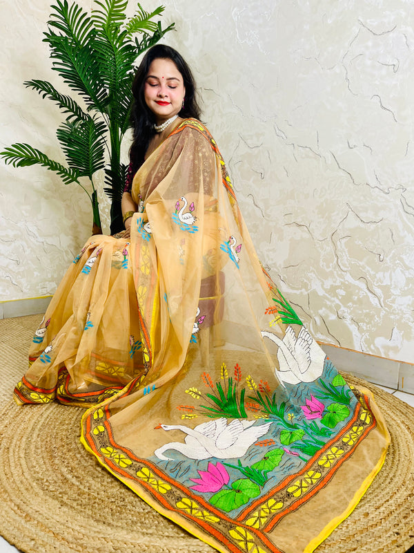 Woman seated in beige-gold Kantha stitch organza saree with swan and lotus embroidery, pallu draped forward
