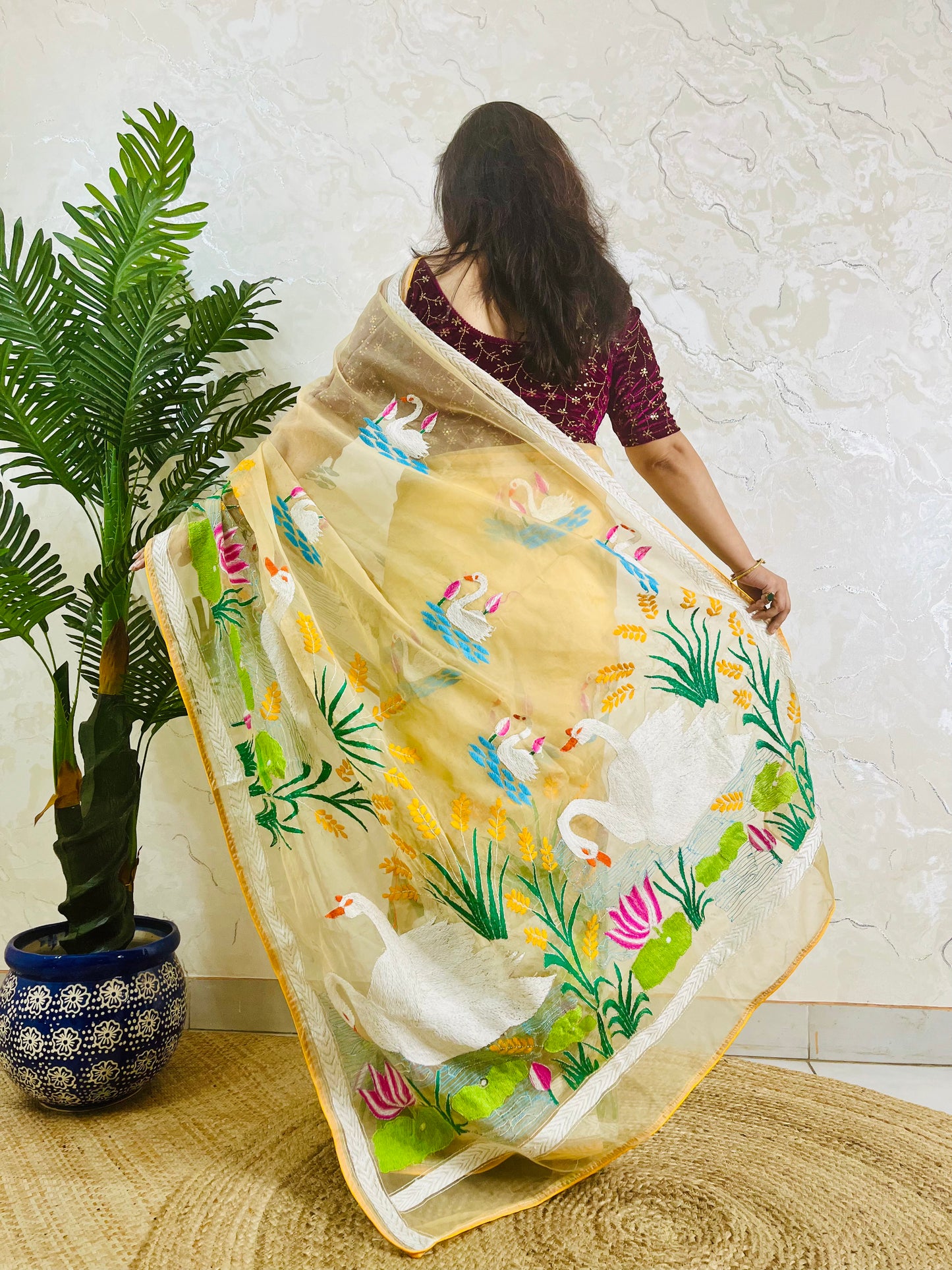 Woman wearing beige gold hand-embroidered swan lotus Kantha saree, back standing pose