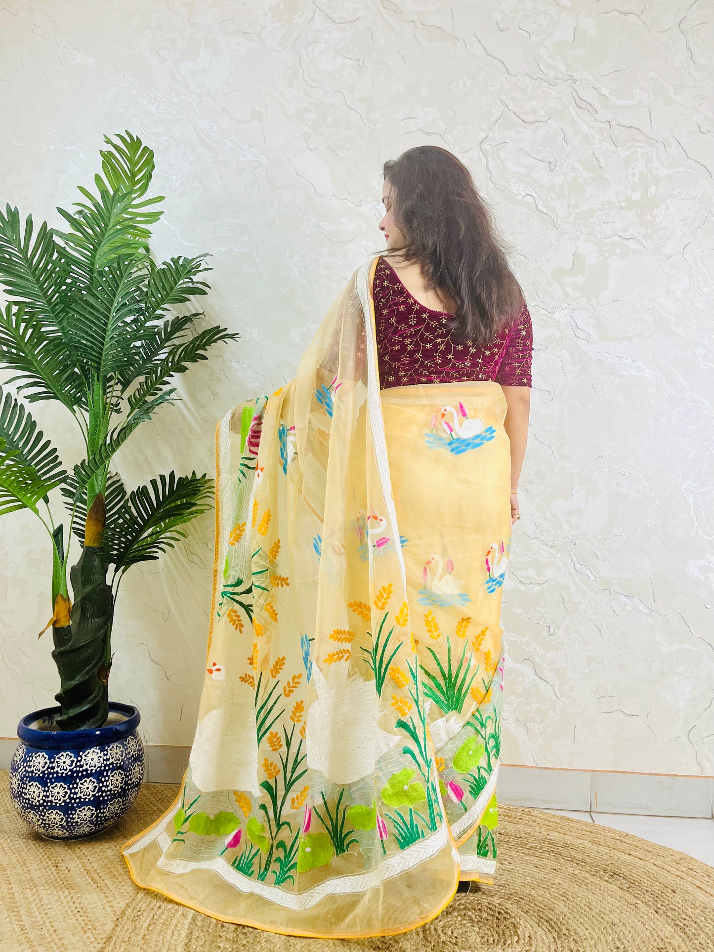 Woman wearing beige gold hand-embroidered swan lotus Kantha saree, back standing pose