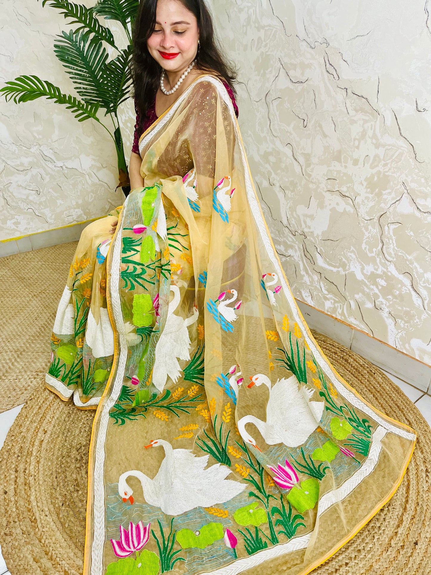 Handcrafted swan and lotus Kantha stitch saree in beige gold, seated draped view