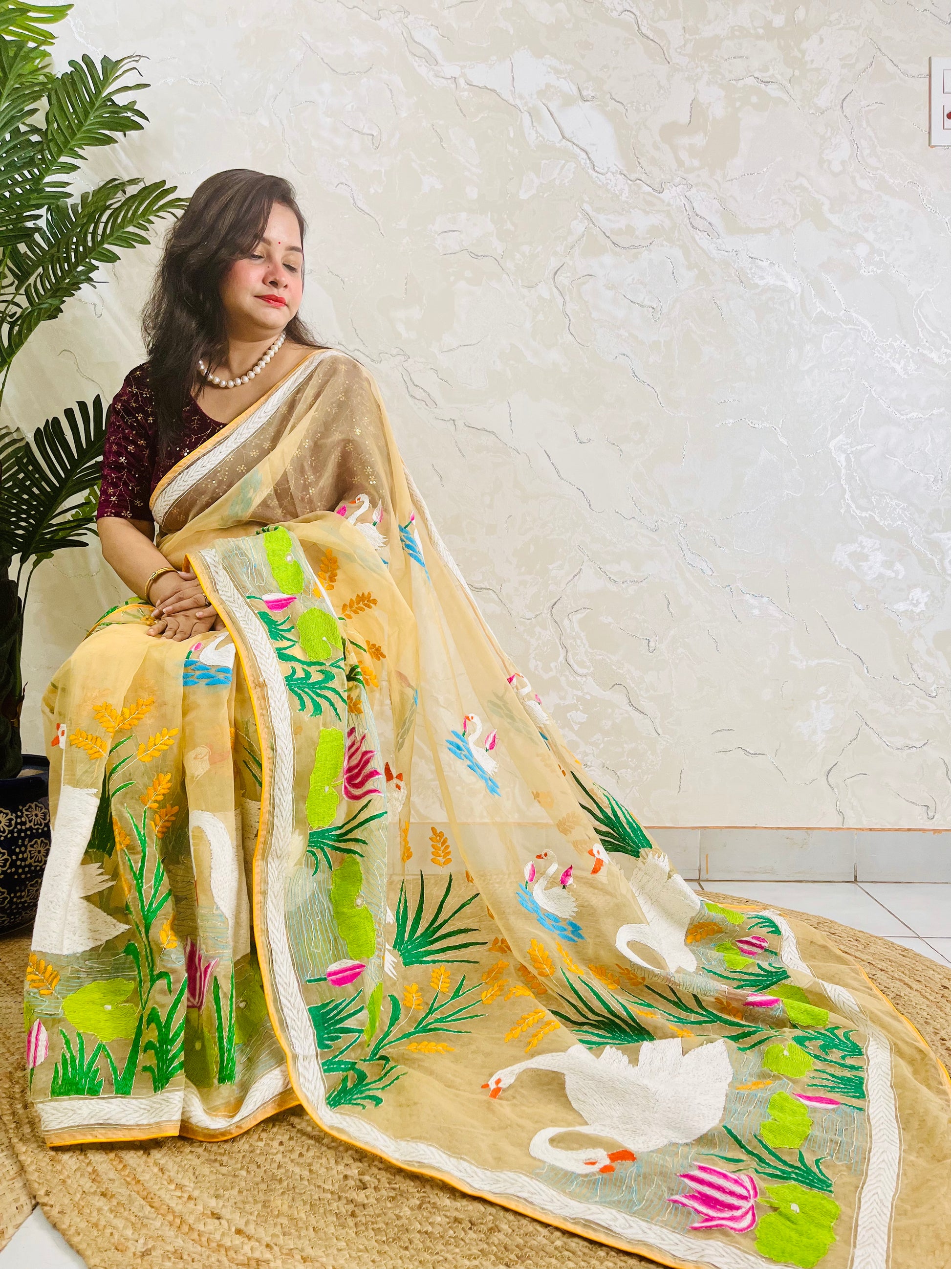 Beige gold Kantha stitch saree with swan and lotus embroidery, side seated view