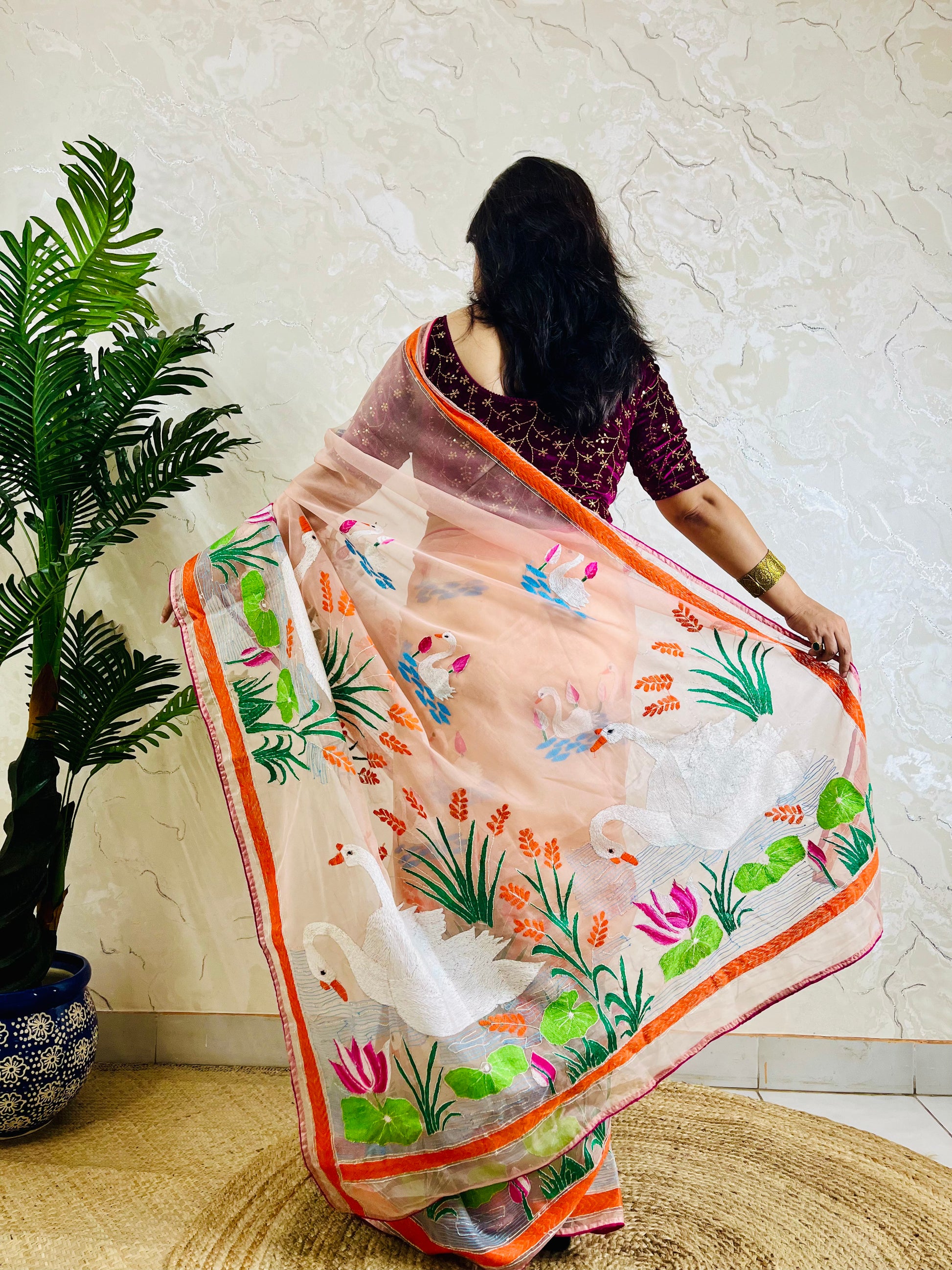 Peach-pink Kantha stitch organza saree with hand-embroidered swan and lotus motif, back standing pallu view