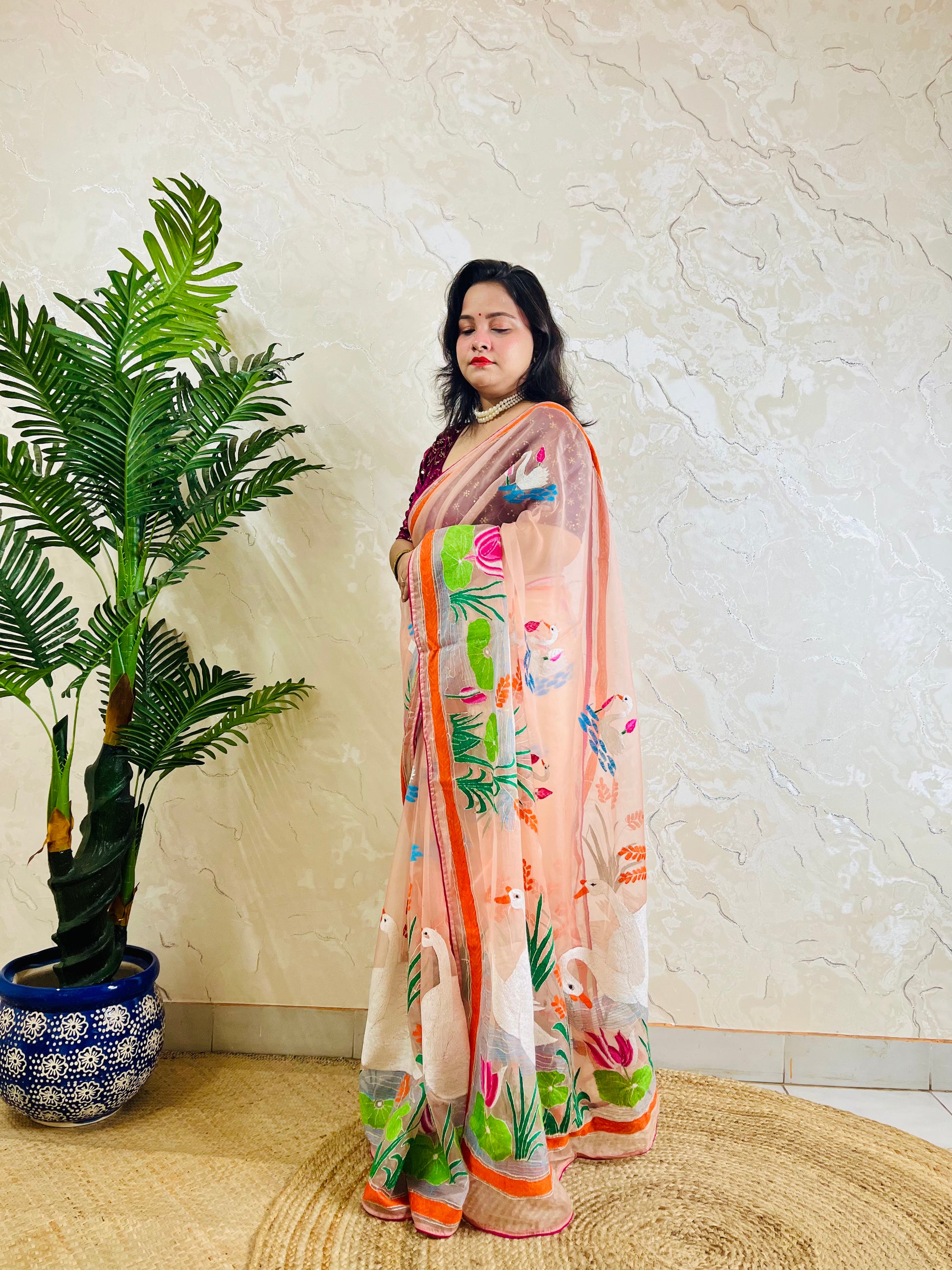 Peach-pink Kantha stitch organza saree with hand-embroidered swan and lotus motif, back standing pallu view