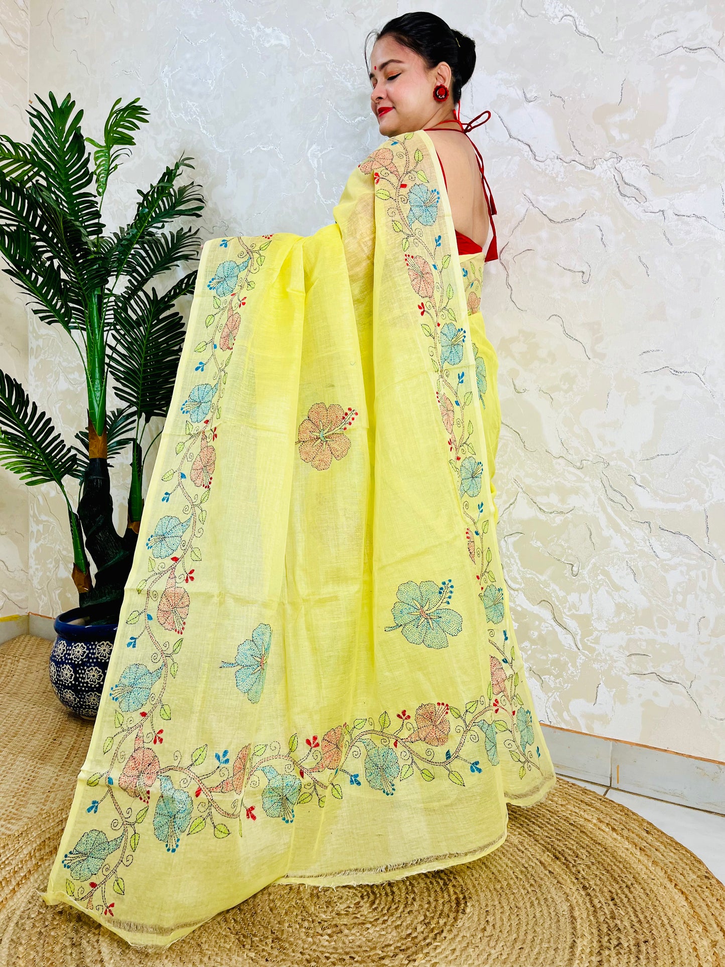 Woman standing in pastel yellow Tussar silk saree with floral Kantha embroidery