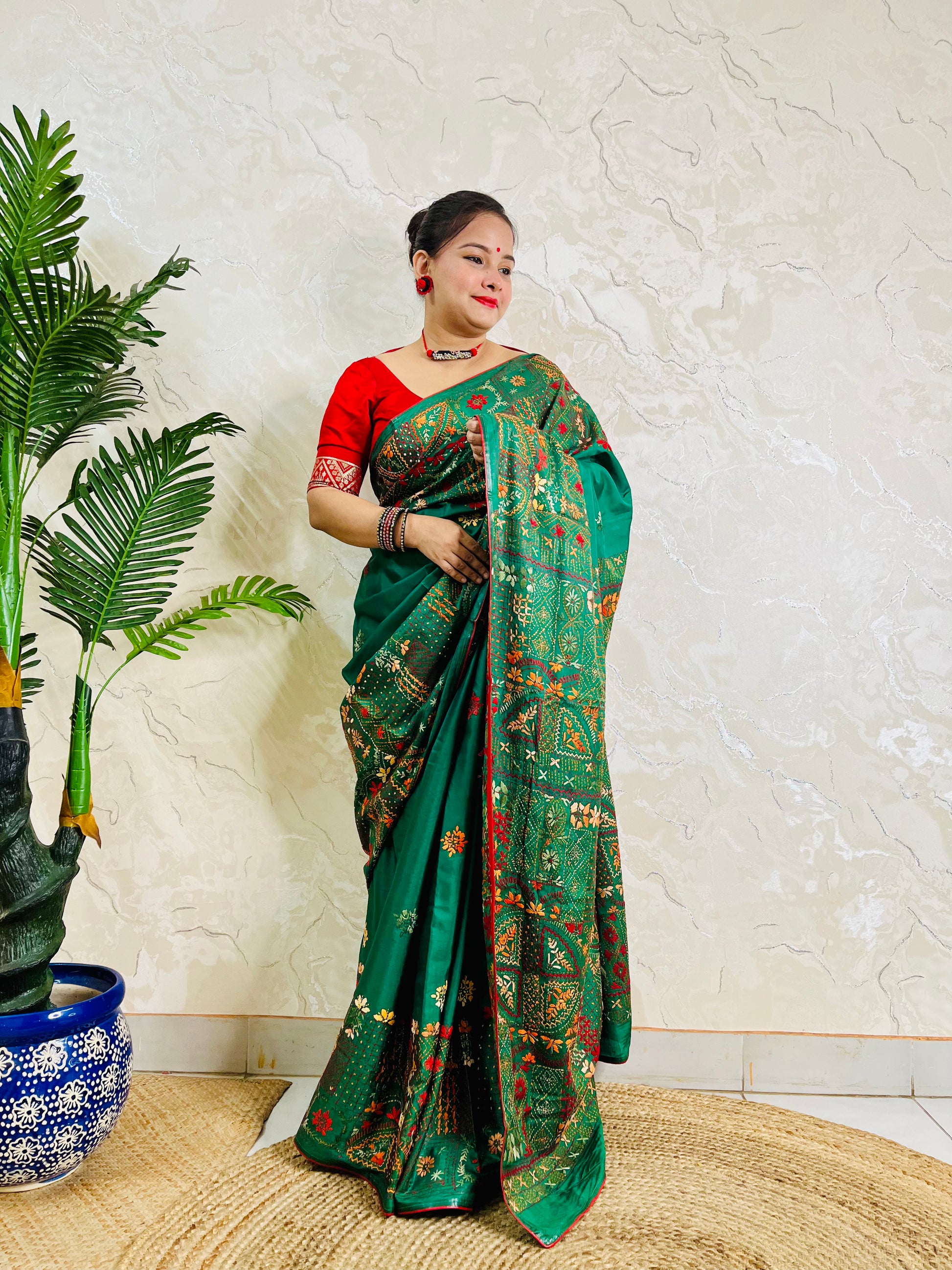 Woman standing in emerald green Bangalore silk saree with Lambani embroidery