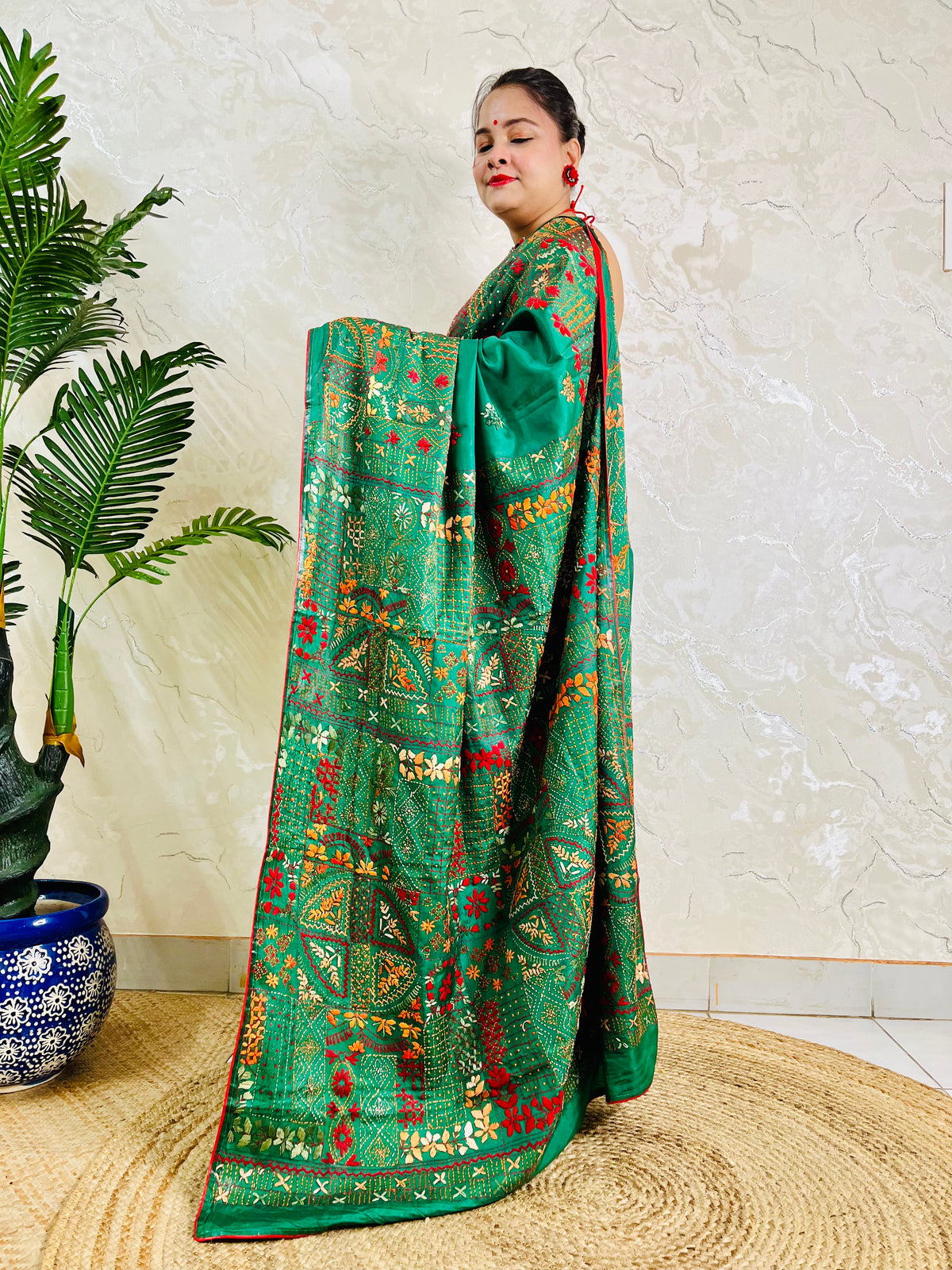 Woman standing in emerald green Bangalore silk saree with Lambani embroidery