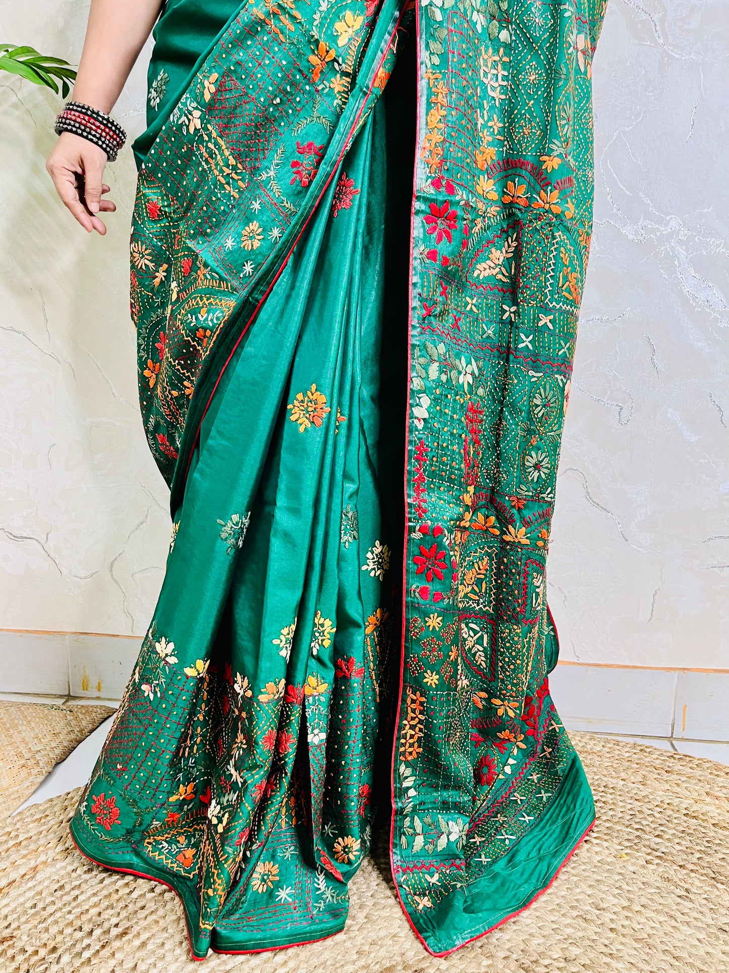 Close-up seated view of emerald green Lambani embroidered saree with red border