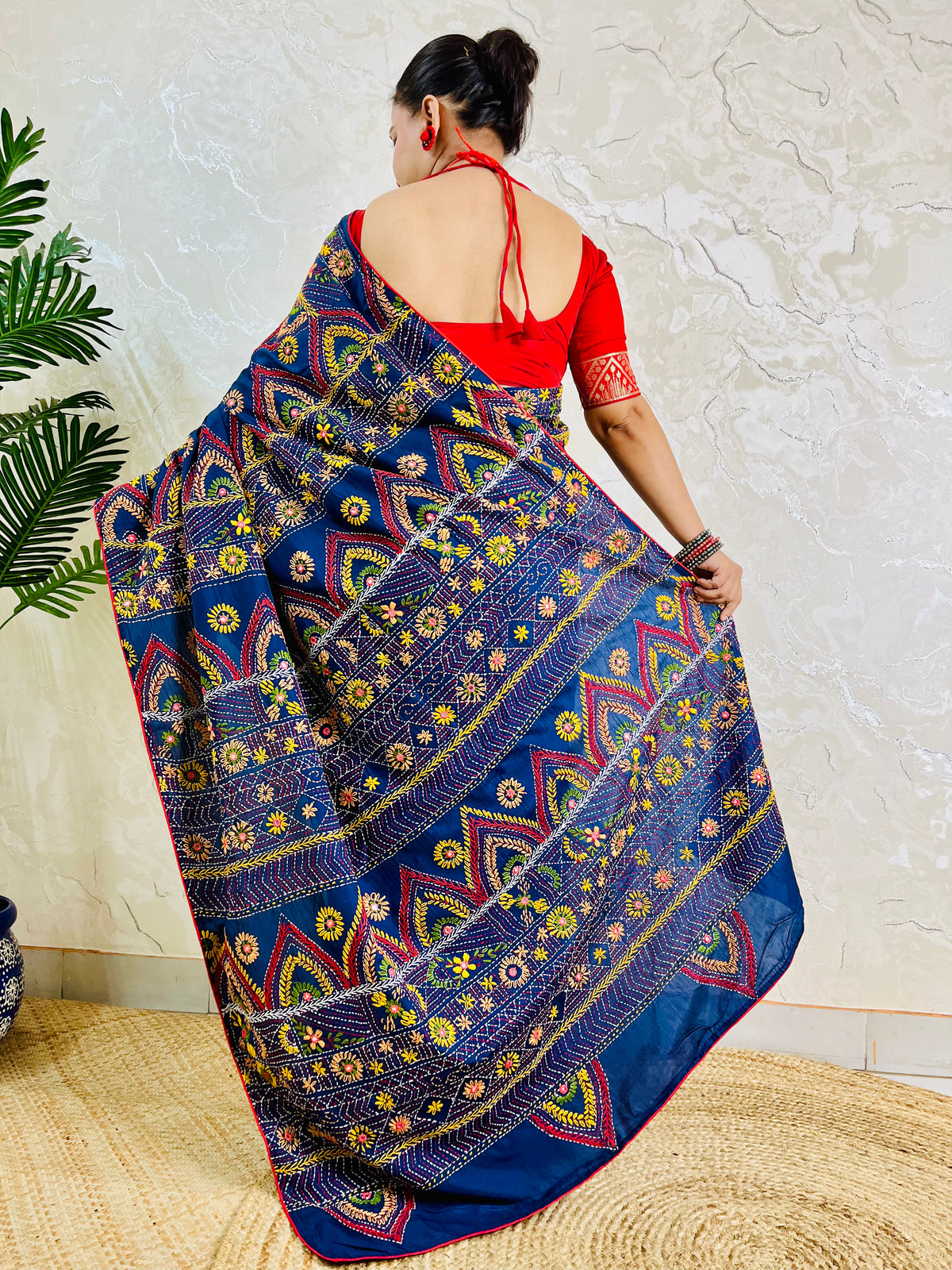 Deep indigo Lambani saree with red and gold arch motif embroidery, back standing view