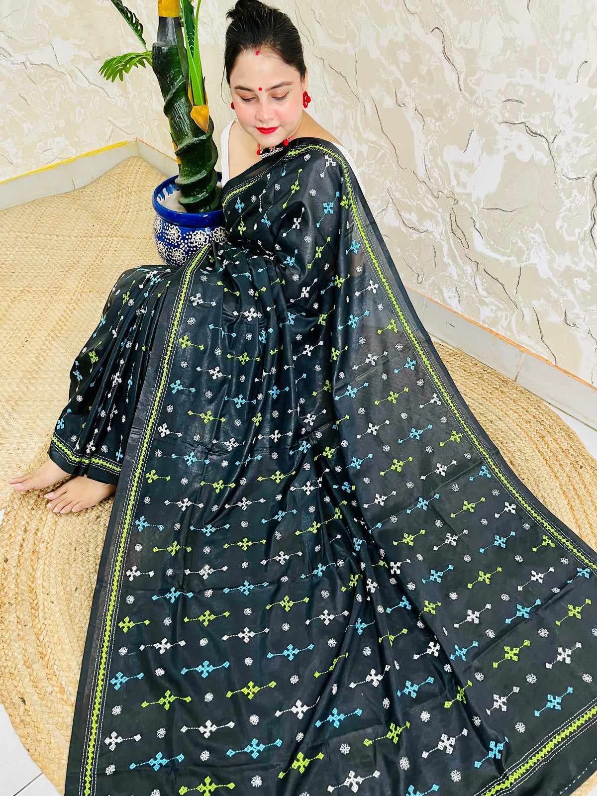 Woman seated wearing black Kutch embroidery saree, Bangalore silk fabric detail