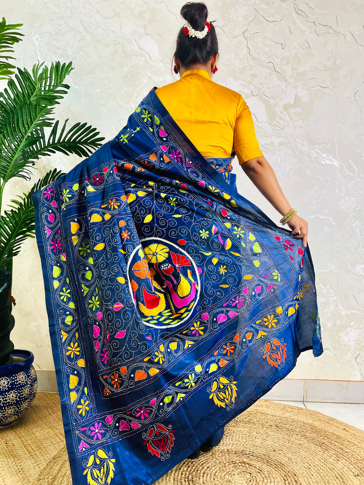 Back standing view of ink blue Kantha stitch saree with swan and floral border