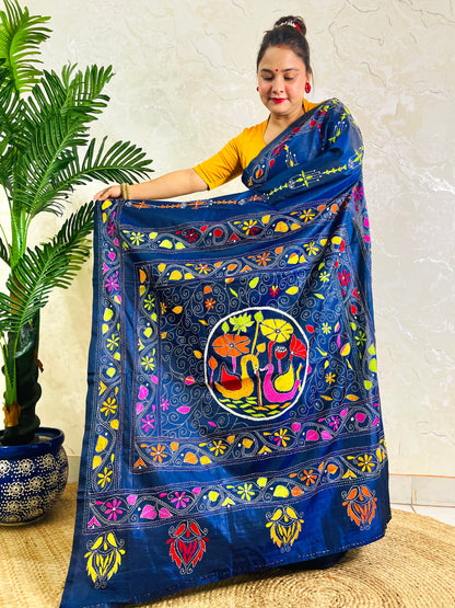 Woman holding open pallu of ink blue Kantha saree showing swan medallion