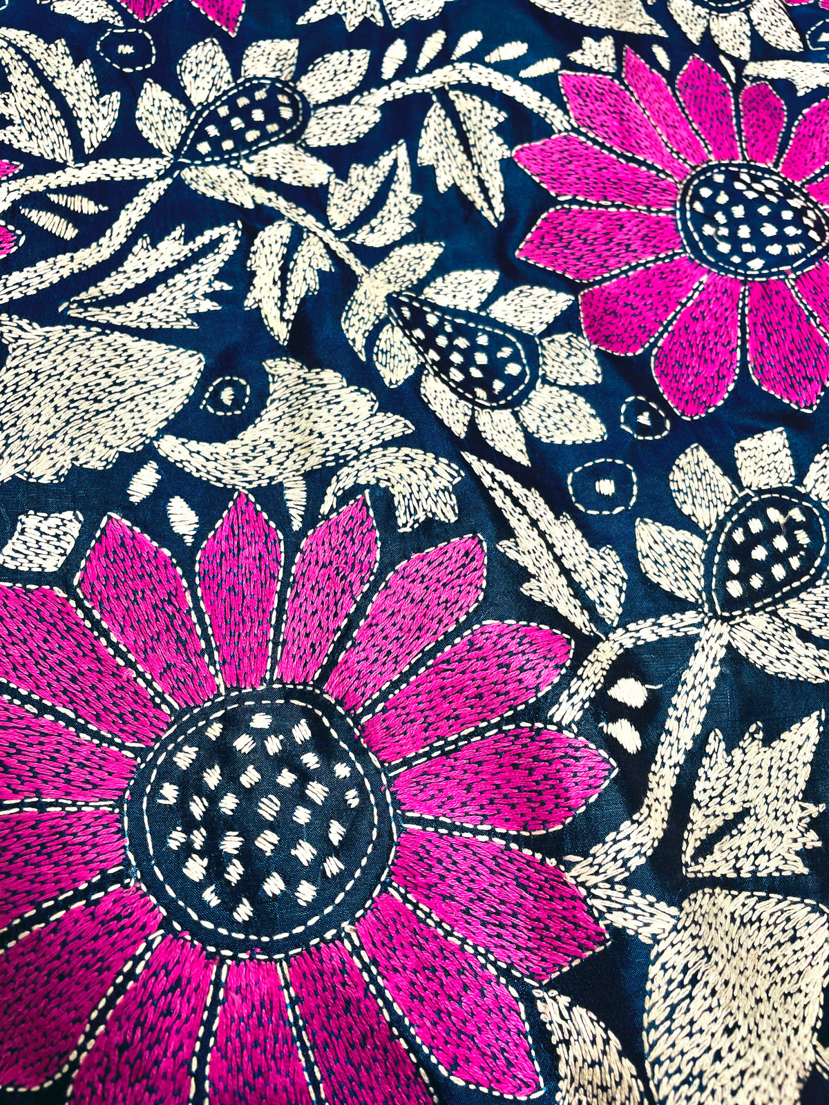 Close-up of magenta sunflower Kantha stitch embroidery with white vines on peacock blue silk