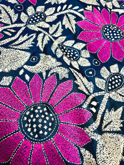 Close-up of magenta sunflower Kantha stitch embroidery with white vines on peacock blue silk