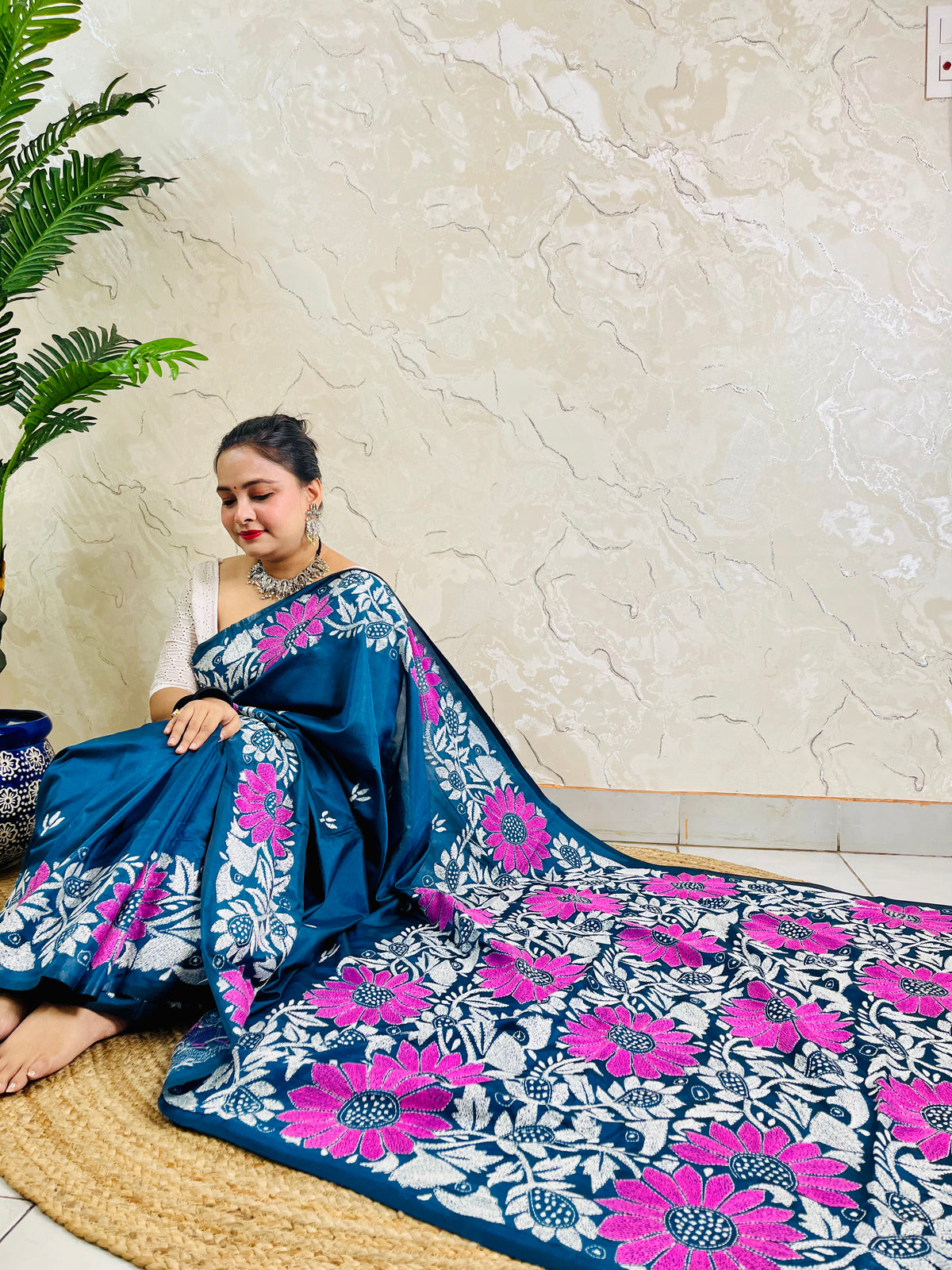 Seated drape of peacock blue Kantha saree with sunflower motif border and plain body