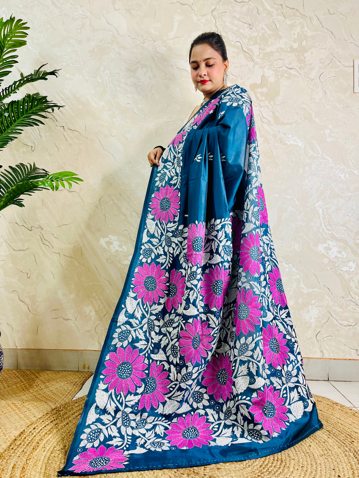 Pallu held open showing rows of magenta sunflowers and white leaf vines on peacock blue saree