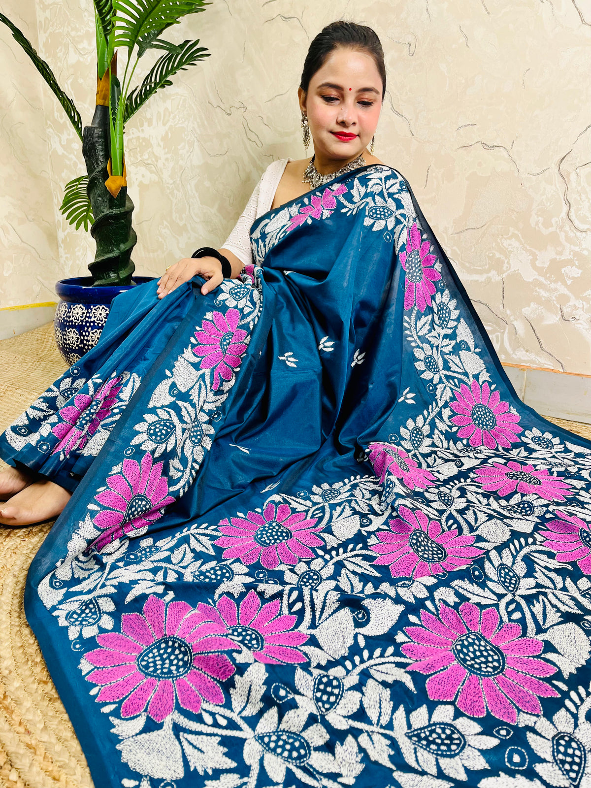 Seated drape of peacock blue Kantha saree with sunflower motif border and plain body