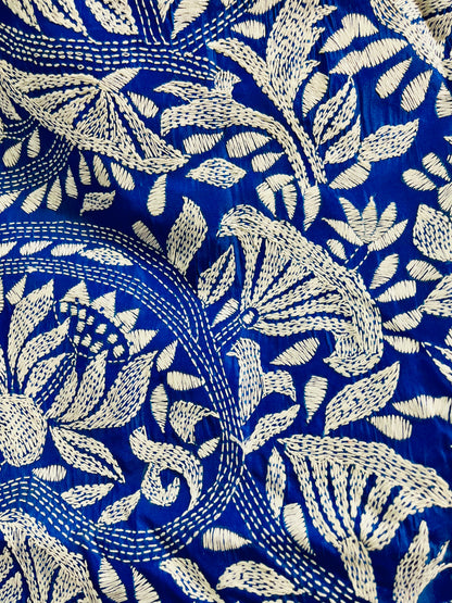 Close-up of white Kantha running stitch branches, leaves and seed-pod blooms on royal blue silk