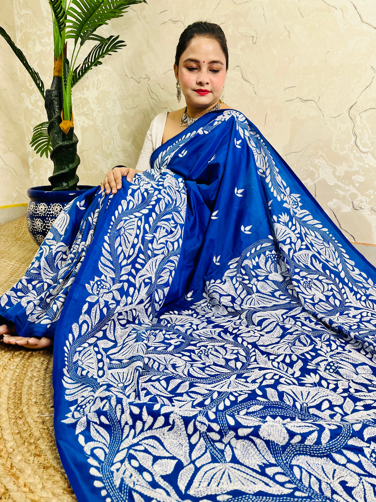 Seated close view of royal blue Kantha stitch saree pallu with dense white leaf work