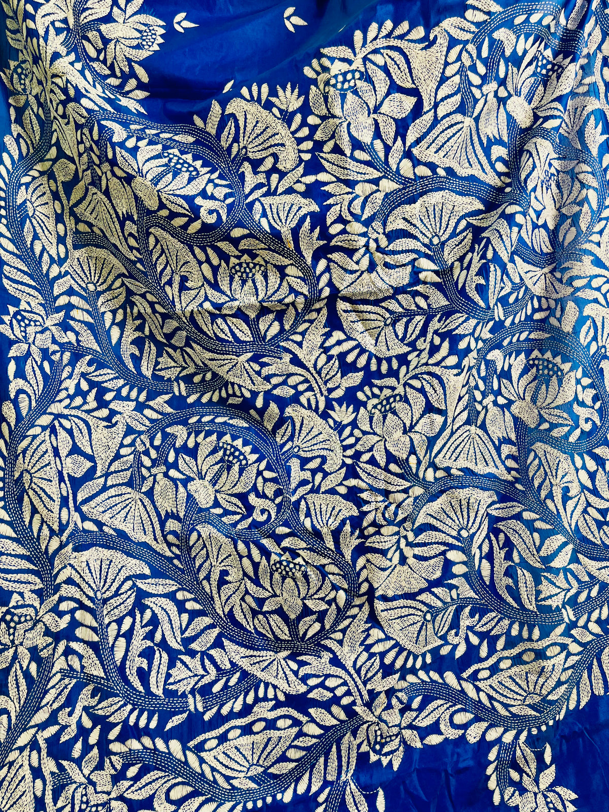 Close-up of white Kantha running stitch branches, leaves and seed-pod blooms on royal blue silk