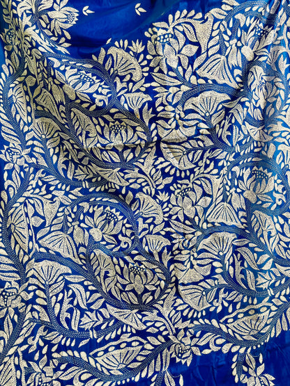Close-up of white Kantha running stitch branches, leaves and seed-pod blooms on royal blue silk
