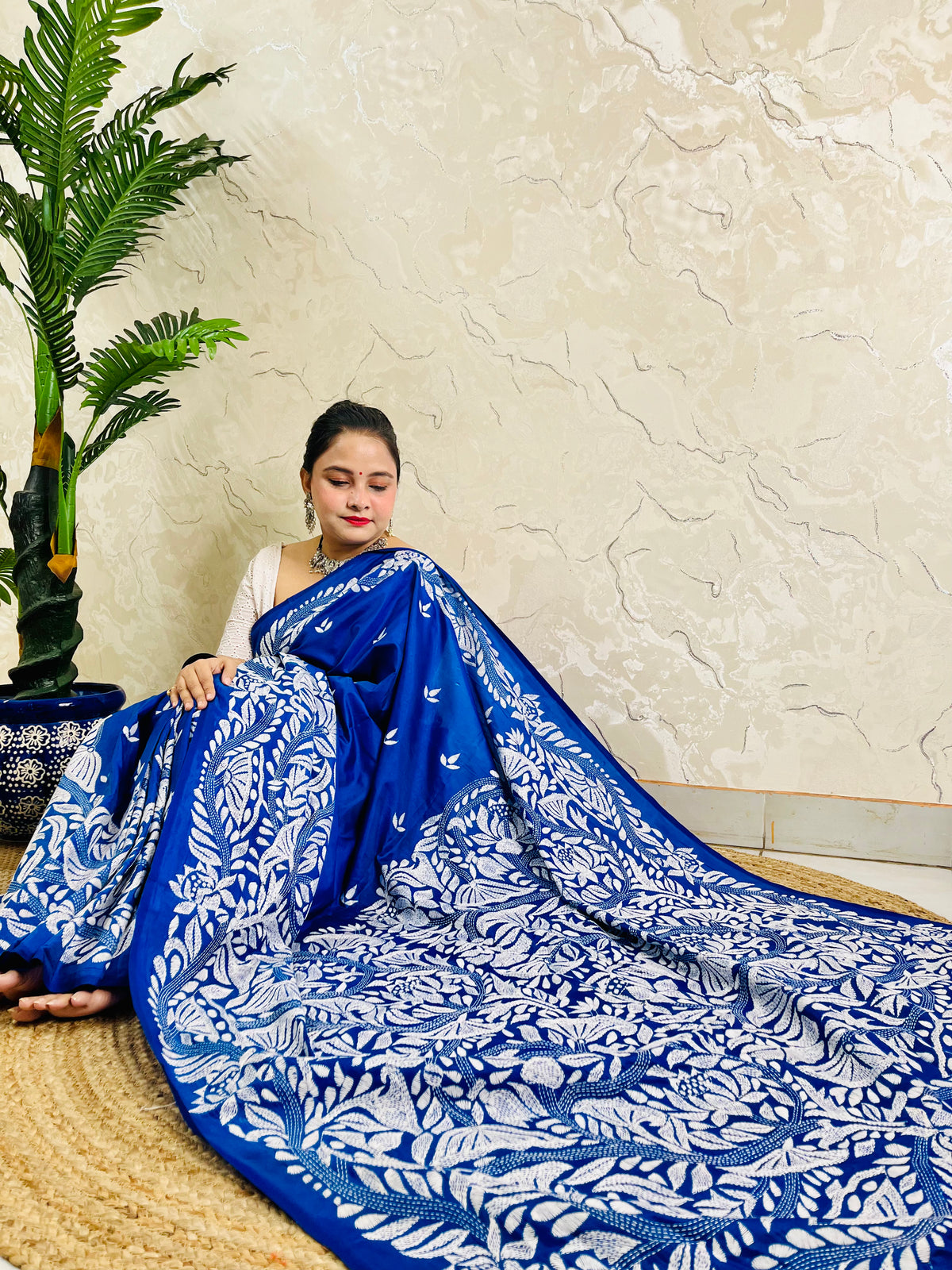 Seated drape of royal blue Kantha saree spread out showing looping branch and lotus-like bloom embroidery