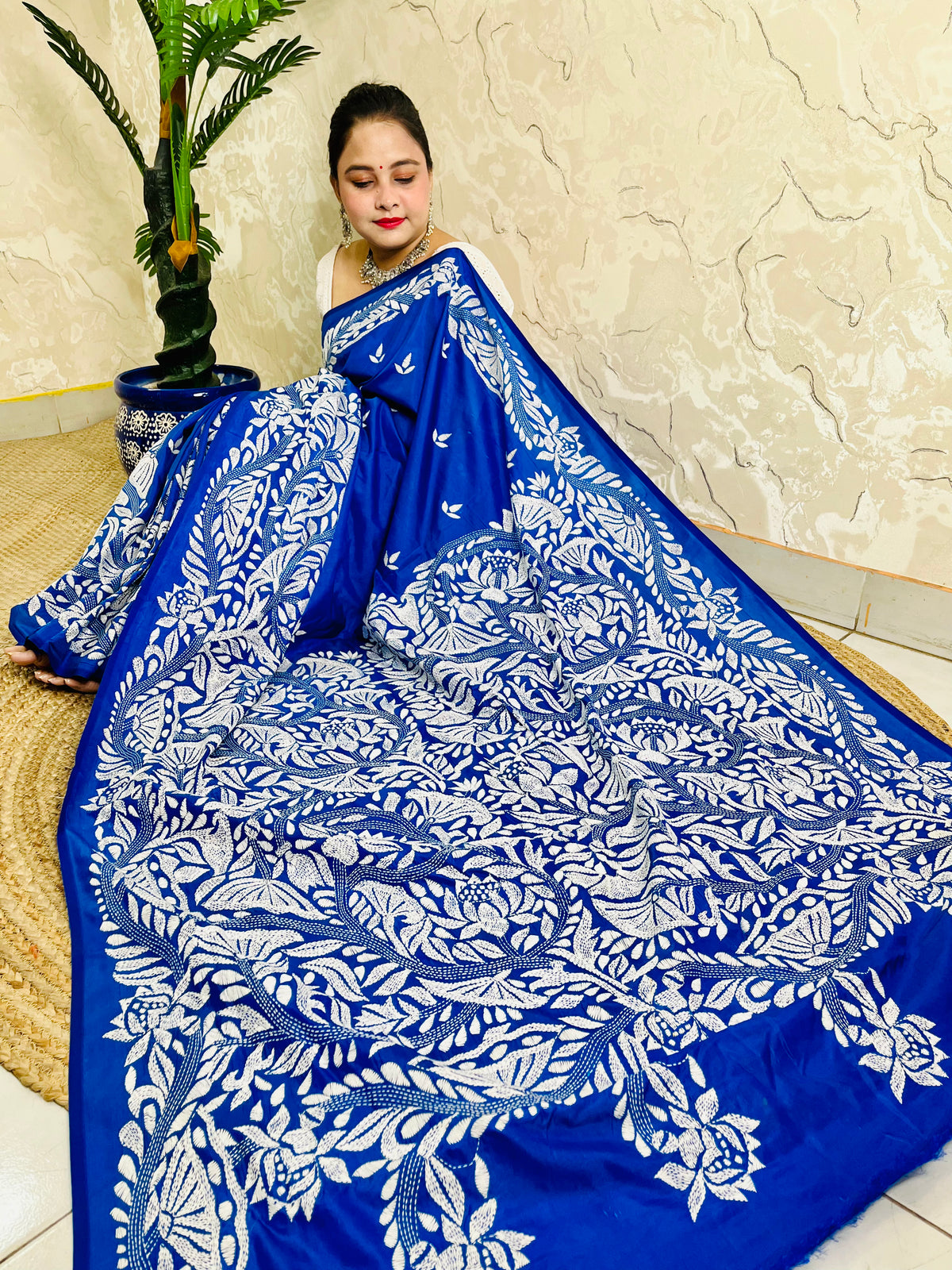 Seated close view of royal blue Kantha stitch saree pallu with dense white leaf work