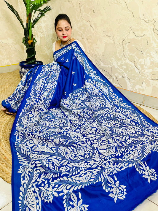 Seated close view of royal blue Kantha stitch saree pallu with dense white leaf work