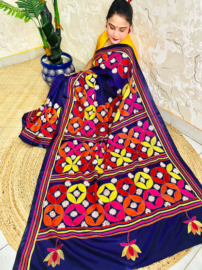 Woman seated in deep indigo Kantha saree with multicolour geometric border, side view