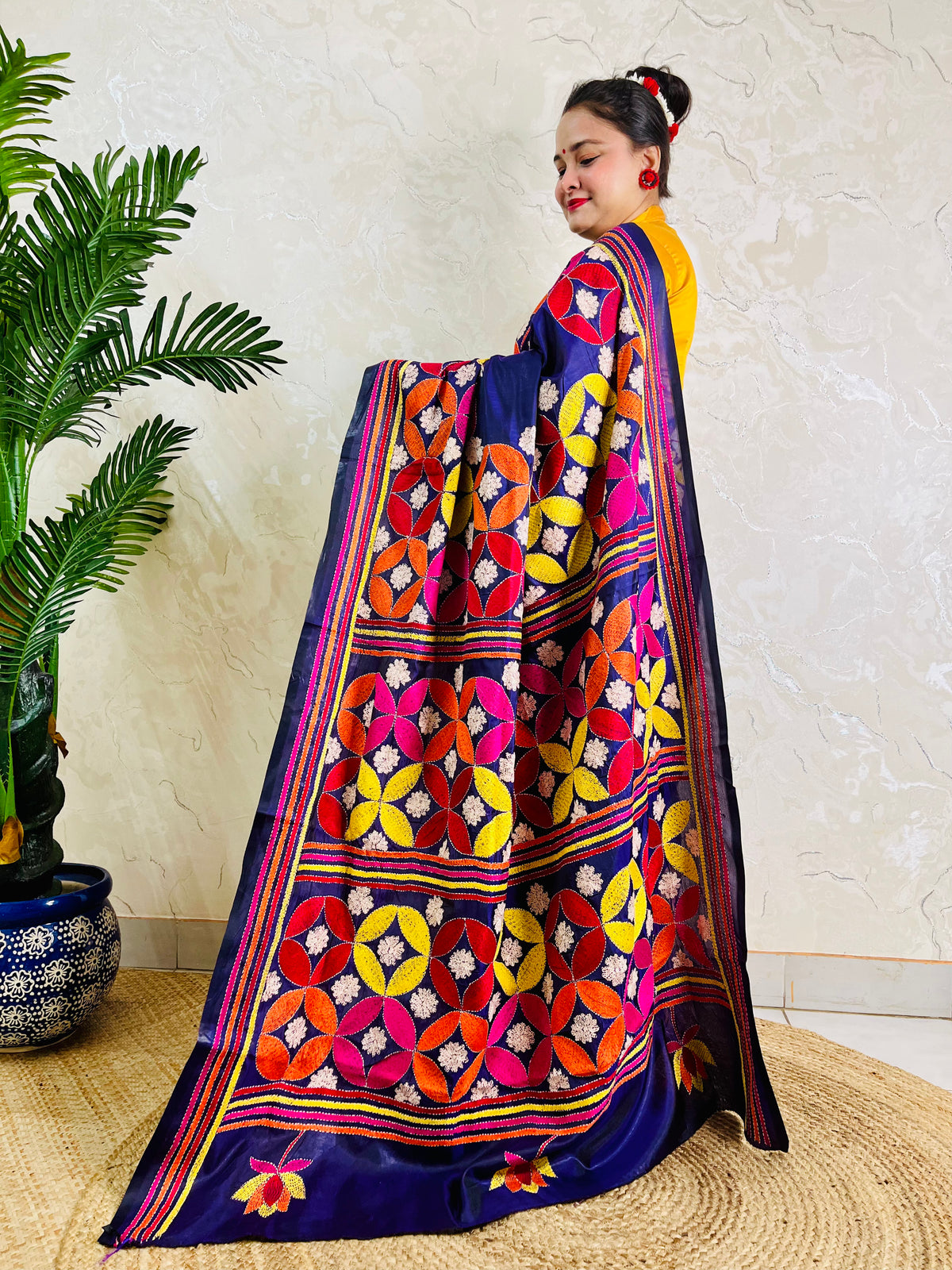 Woman draping deep indigo Kantha stitch saree, pallu spread standing view