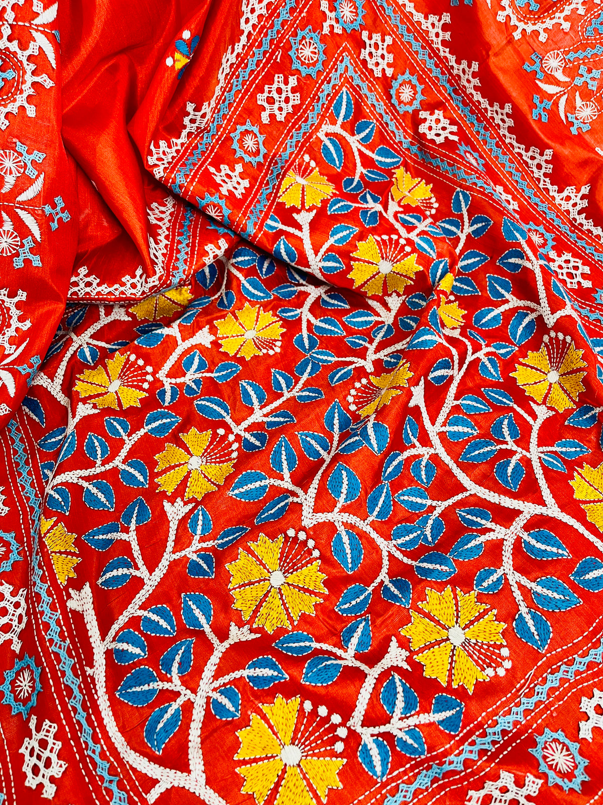Close-up of Kantha stitch blue leaves and yellow flowers on vermilion Bangalore silk