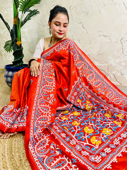 Seated pose in vermilion Kutch and Kantha fusion saree with paisley hem border
