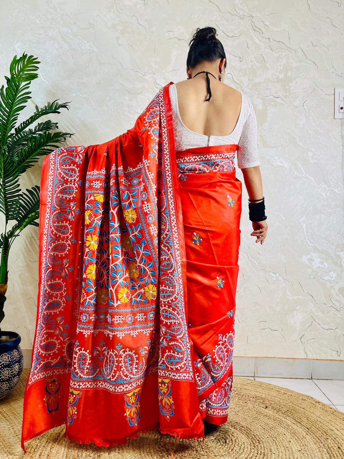 Detail of white and sky blue Kutch work cross-stitch lattice beside Kantha leaf motifs on vermilion silk
