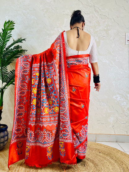 Detail of white and sky blue Kutch work cross-stitch lattice beside Kantha leaf motifs on vermilion silk