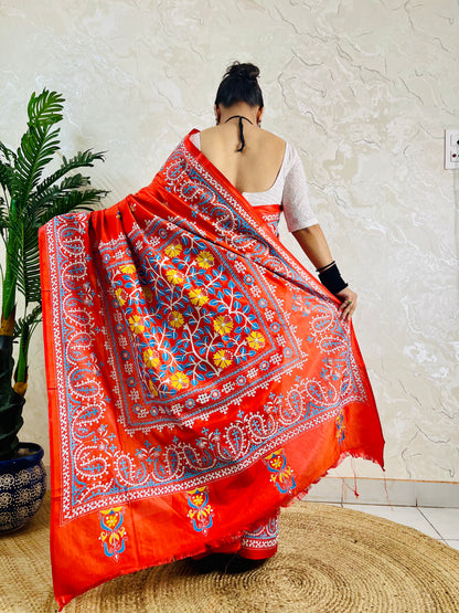 Detail of white and sky blue Kutch work cross-stitch lattice beside Kantha leaf motifs on vermilion silk