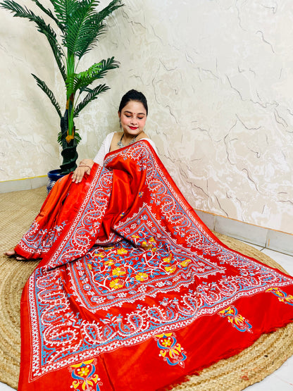 Seated pose in vermilion Kutch and Kantha fusion saree with paisley hem border