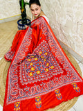 Top view of seated drape in vermilion saree with flower, leaf and paisley embroidery