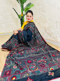 Woman seated in black Bangalore silk saree with Lambani thread embroidery