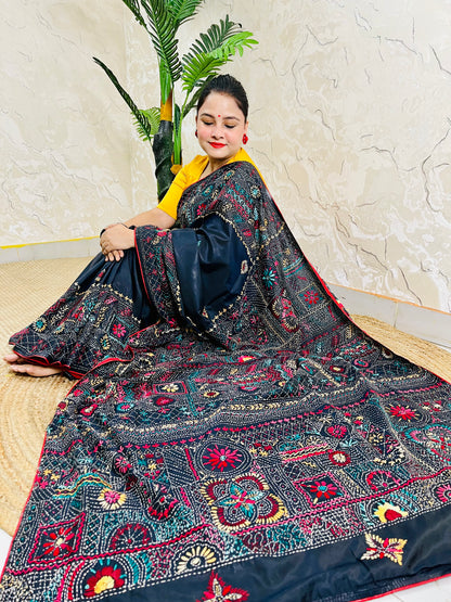 Woman seated in black Bangalore silk saree with Lambani thread embroidery