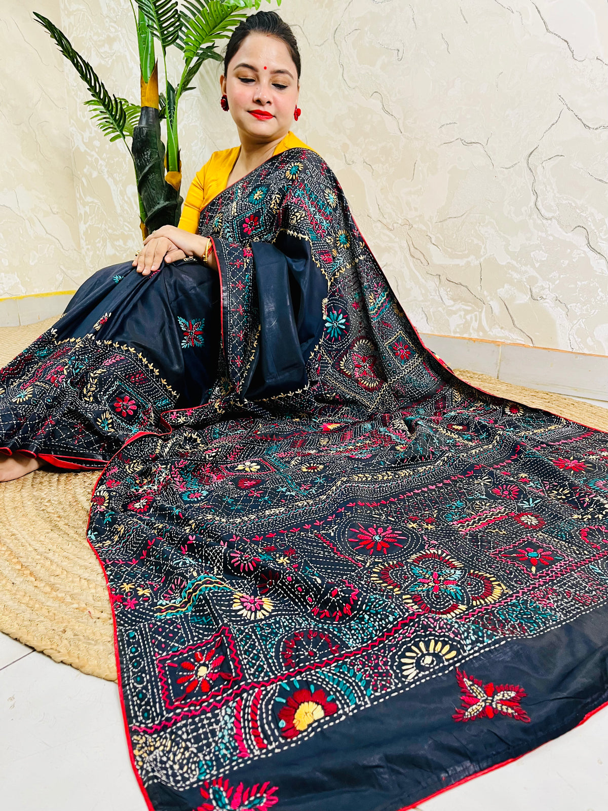 Woman seated in black Bangalore silk saree with Lambani thread embroidery