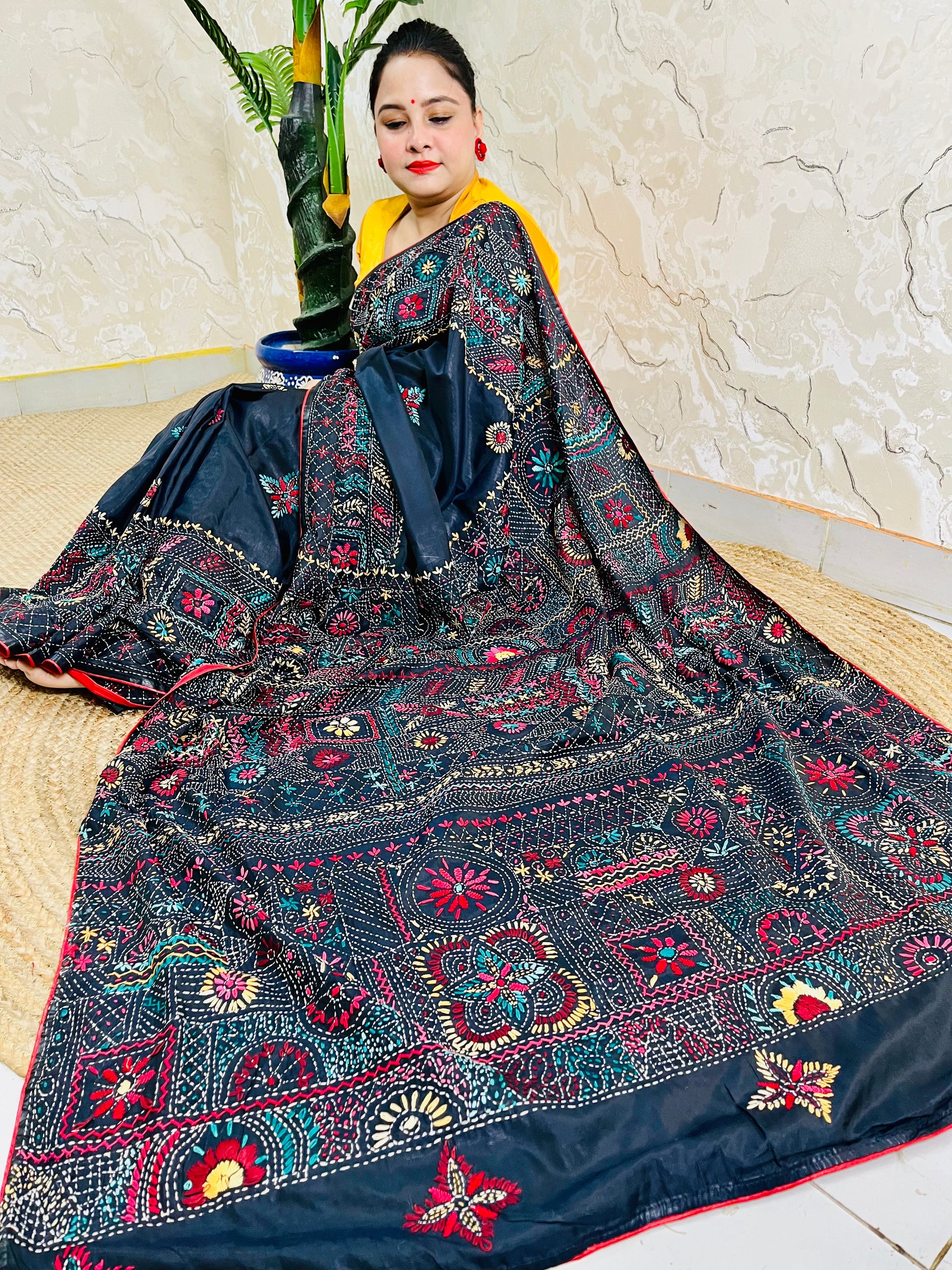 Woman seated in black Bangalore silk saree with Lambani thread embroidery