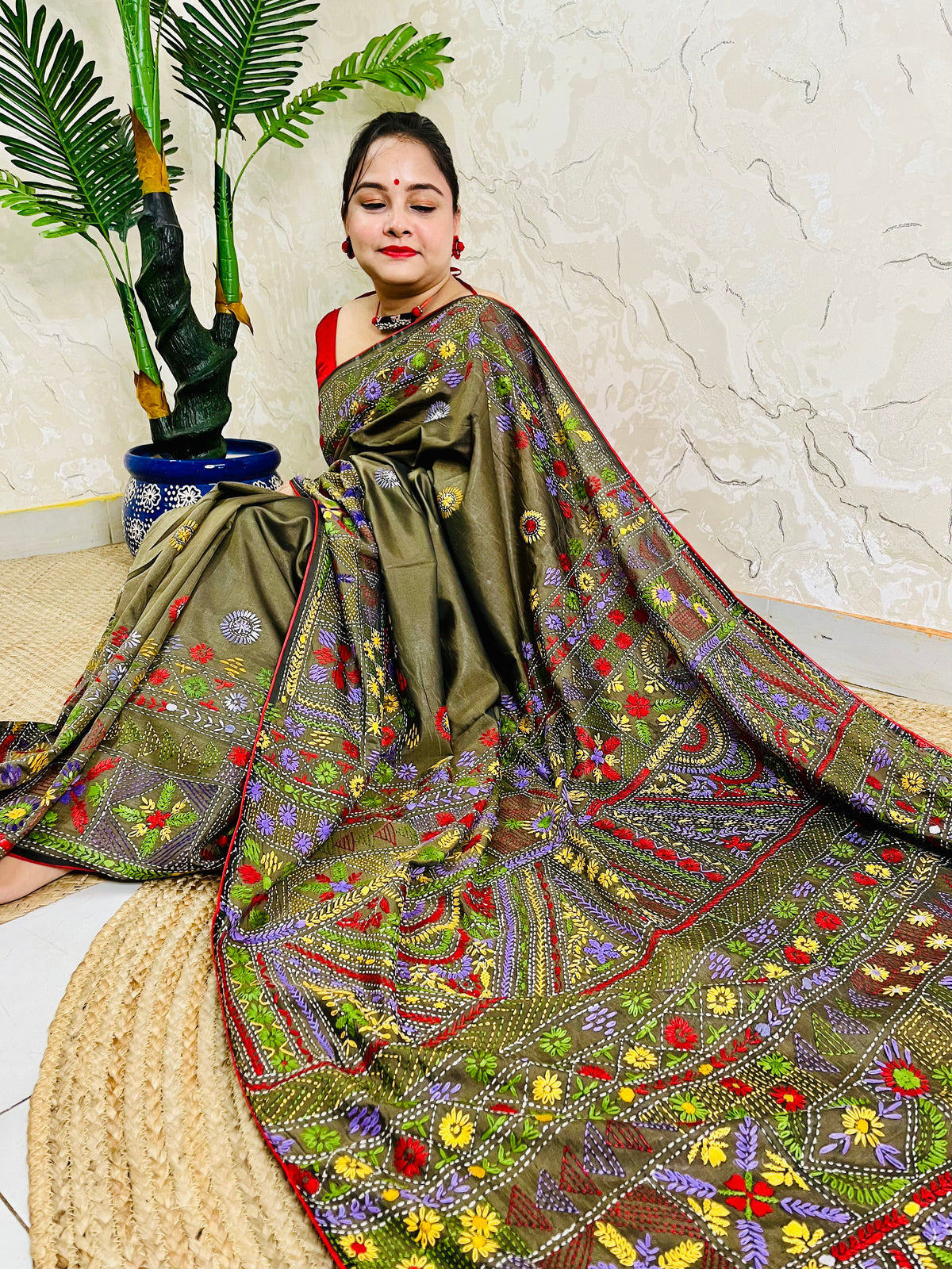 Front seated view of moss green Lambani stitch saree with floral border