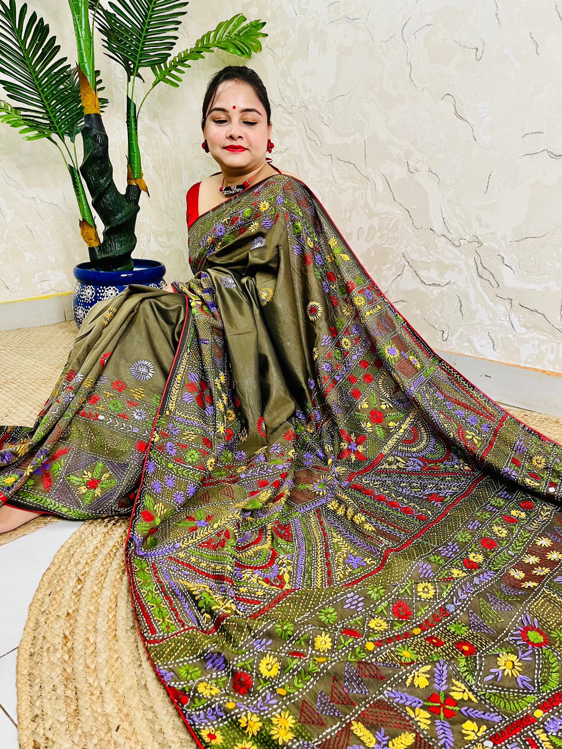 Front seated view of moss green Lambani stitch saree with floral border