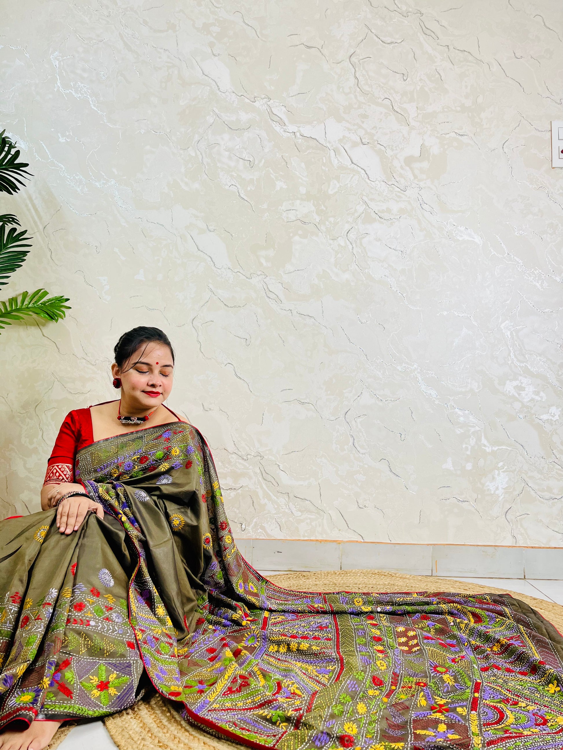 Woman seated in moss green Bangalore silk saree with Lambani embroidery