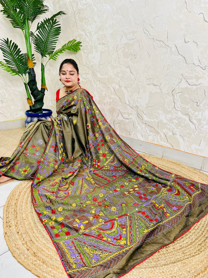 Woman seated in moss green Bangalore silk saree with Lambani embroidery