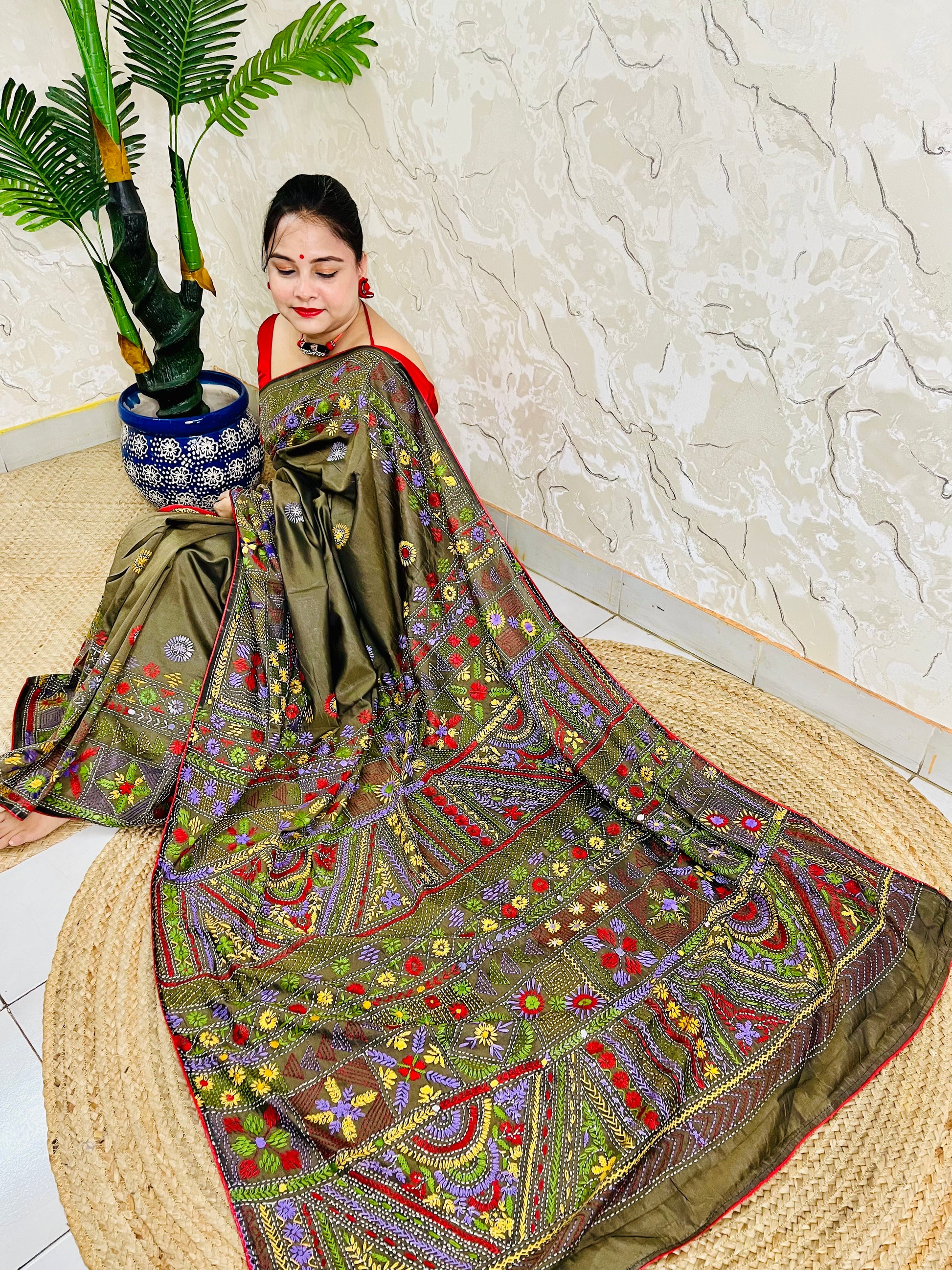 Front seated view of moss green Lambani stitch saree with floral border